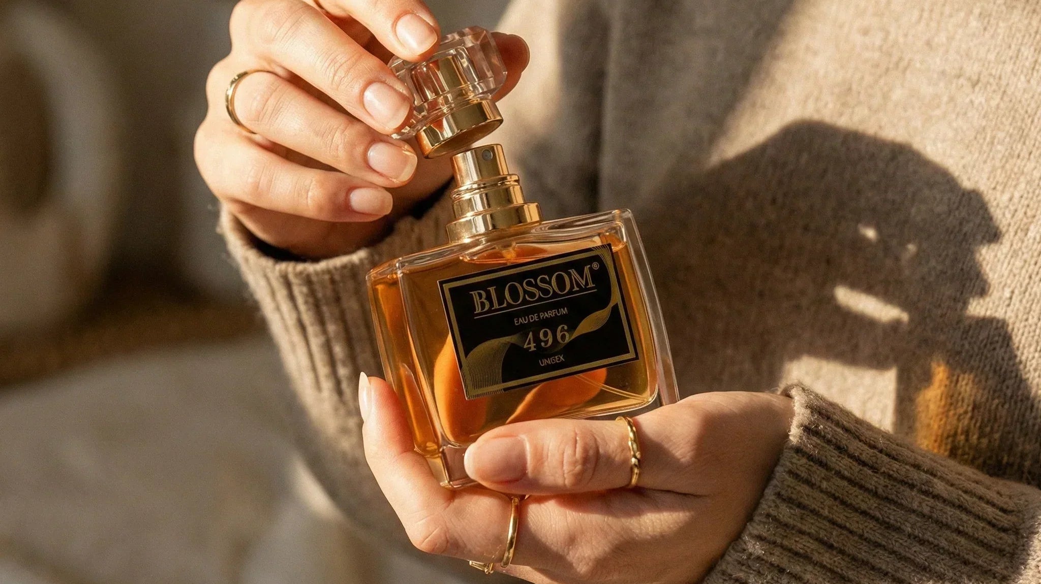 Blossom 496 - Inspired by Vanilla 28 perfume held in a woman’s hands. The woman wears a greyish-brown sweater.