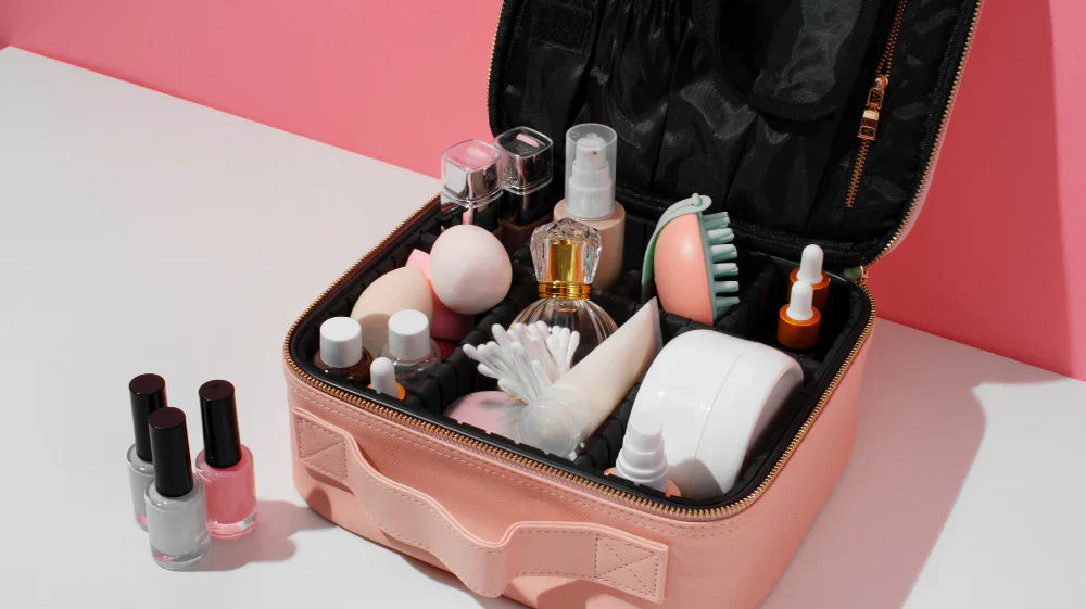 Various cosmetic products and a perfume bottle inside a small pink suitcase.
