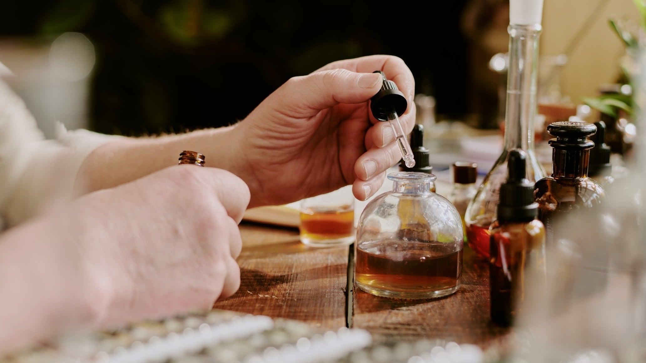 Person carefully measuring perfume oil.