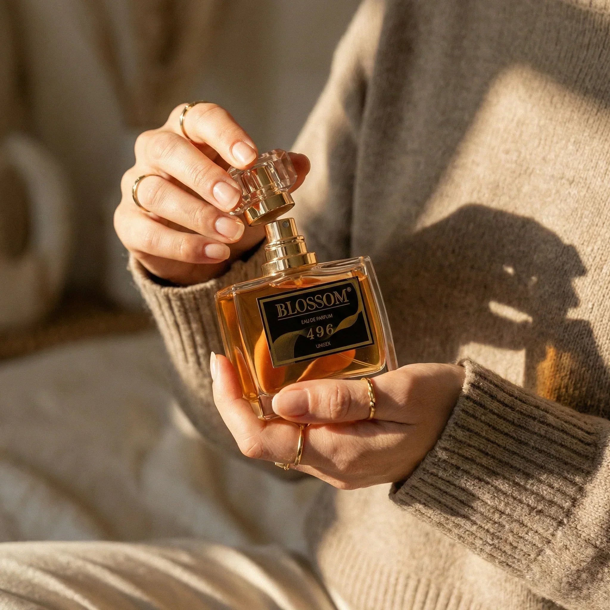 Blossom 496 - Inspired by Vanilla 28 perfume held in a woman’s hands. The woman wears a greyish-brown sweater.